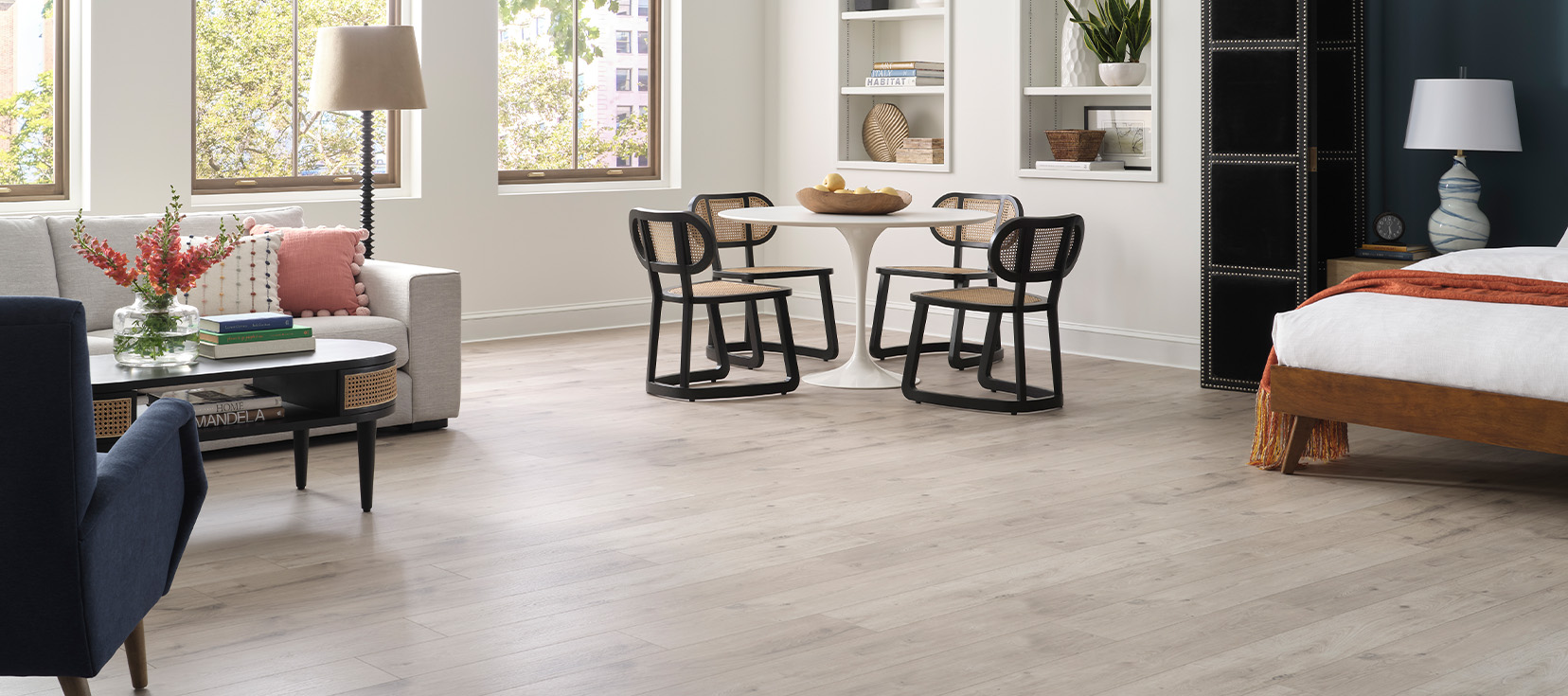 Sosebee Cove laminate flooring in a light gray wood look, installed throughout a bright open-concept living and bedroom space.